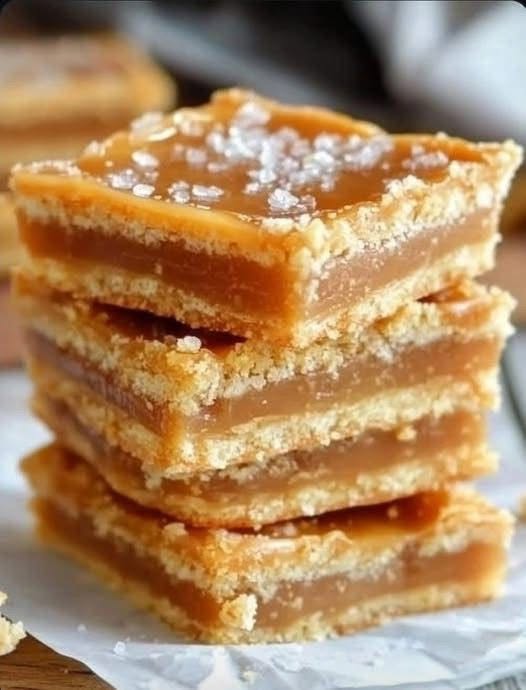 Stacked salted caramel shortbread bars with golden cookie layers, thick caramel filling, and flaky sea salt.