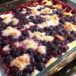 Blackberry cobbler with bubbling purple berry filling and golden baked topping in a rectangular glass dish.