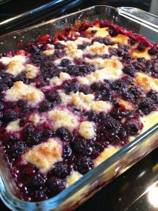 Blackberry cobbler with bubbling purple berry filling and golden baked topping in a rectangular glass dish.