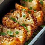 Thick roasted cauliflower steaks with golden brown edges and chopped parsley in a rectangular serving dish.